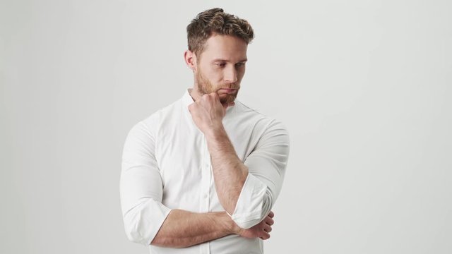 Handsome young optimistic man in white shirt isolated over white wall background