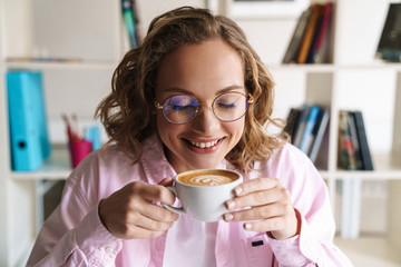 Photo of cheerful nice woman smiling and drinking coffee