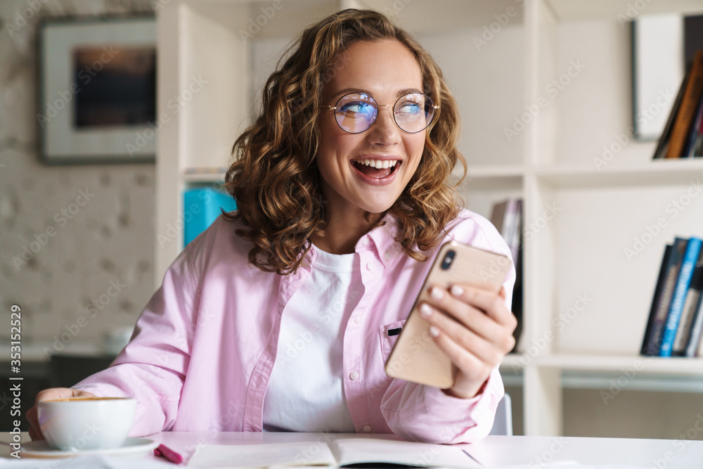 Poster Photo of smiling nice woman using cellphone and drinking coffee