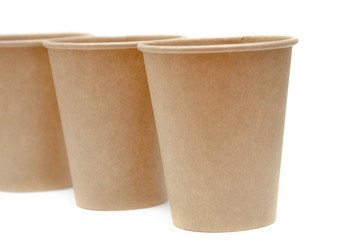 Brown paper cup for coffee, tea, a drink from environmental materials on a white background. Three glasses stand one after another diagonally. Glasses go far into perspective
