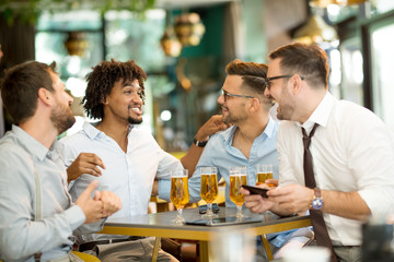 young businessmen in a cafe use a mobile phone and have fun while drinking cold beer