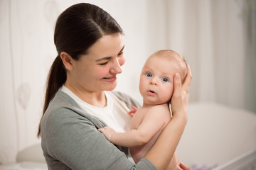 Close up portrait of beautiful young mother girl kissing her newborn baby