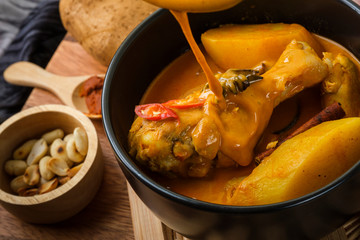 Massaman Curry With Chicken and Thai herbs with wood background texture