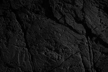 Black grunge background. Rough stone surface with cracks. Black rock texture. Mountains texture. Close-up.
