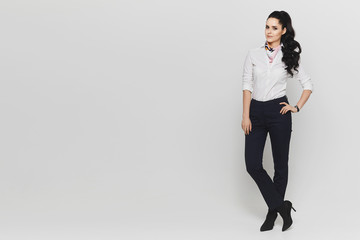 Portrait in the full length of a young woman in white blouse and in dark pants isolated at white background. Copy space on the left