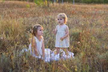 two girls play in a field at sunset