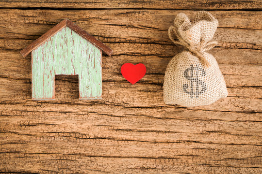 A house model and money bag and red heart for loans real estate concept.