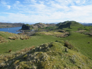 View over grassy sand dunes to strait, island, and mountains in distance