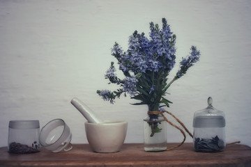 Veronica blue flowers in a glass bottle and seeds in a glass bottle.