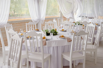 Table setting with blank guest card, plates with napkins and cutlery, copy space. Place setting at wedding reception. Round table served for banquet in restaurant