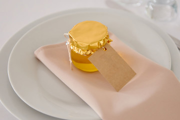Table set with blank guest card, plate with napkin and honey, copy space. Place setting at wedding reception in restaurant