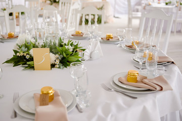 Table setting with blank guest card, plates with napkins and cutlery, copy space. Place setting at wedding reception. Round table served for banquet in restaurant