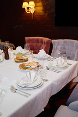 Table setting with sparkling wineglasses, plates with white napkins and cutlery on table, copy space. Place set at wedding reception. Table served for wedding banquet in restaurant