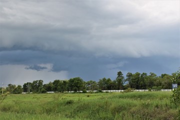 black clouds rainy season and green field.