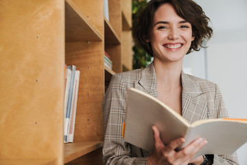 Smiling young woman entrepreneur reading book