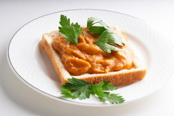healthy toast with zucchini caviar. Russian traditional sandwich served in a plate with herbs on a white table