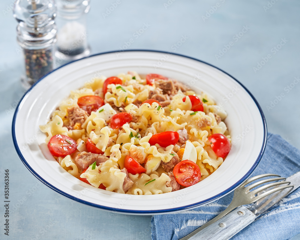 Wall mural Healthy Fusilli or rotini pasta salad with tuna, vine tomatoes and mozzarella cheese on a light background.