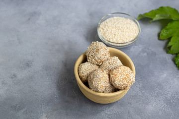 Energy bites without baking are made from ingredients - nuts, cocoa, chocolate, oats and sesame seeds. Located on a gray background.