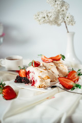 Fruit jam meringue cake garnished with hazelnut chips and strawberries, among lilac flowers. Food photography. Advertising and commercial close up design.