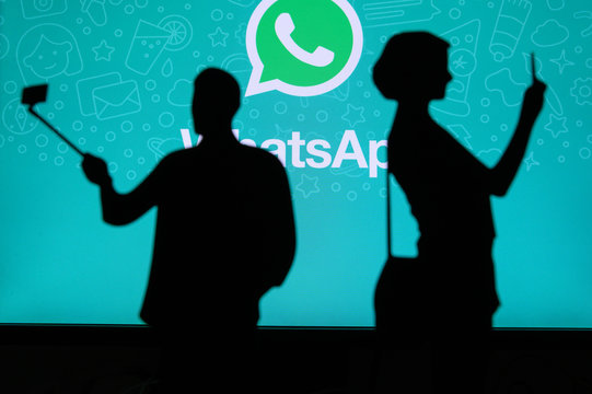 NEW YORK, USA, 25. MAY 2020: WhatsApp cross-platform messaging and Voice over service . Couple taking a photo on a mobile man use a selfie stick. Company logo on screen in background