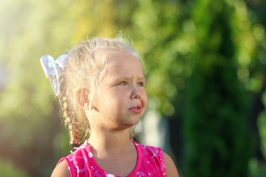 A little girl and looking with digust while playing outdoors on a sunny day. blonde hair and blue eyes. Children protection day concept
