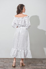 Back view of the pretty girl in a white dress over white wall