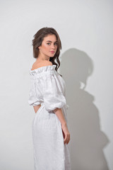 Back view of the pretty girl in a white dress over white wall