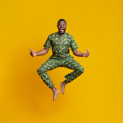 Fototapeta na wymiar Emotional african man jumping in air, wearing traditional clothes