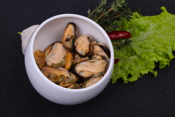 Pickled mussels in the bowl served pepper, garlic and salad