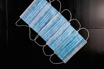 Disposable medical masks to protect against infections and viruses. White and blue layers with elastic bands for ears, on a black background