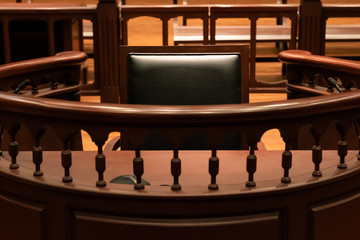 A witness stand with a black seat in the court room infront of tribunal when witness testify of evidence to judge, they will sit at here for testimony of witnesses, it is vintage or retro style - obrazy, fototapety, plakaty