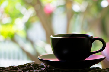 A ceramic cup of coffee on rattan table by a window in the after noon. Relaxing and happy concept.