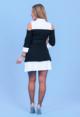 portrait Attractive young blonde model posing in trendy dress isolated at blue studio background. Beautiful girl standing in trendy clothing looking at camera