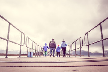 Family On Winter Vacation Walking Across A Bridge Holding Hands