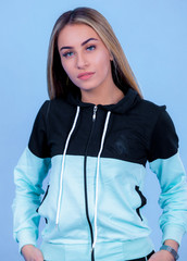 portrait Attractive young blonde pretty young model girl in sportswear posing in blue backround