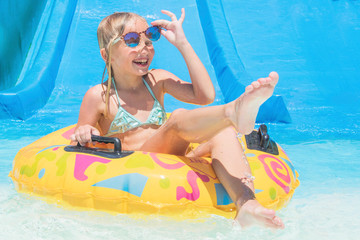 Child on water slide at aquapark. Summer holiday.