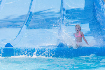 Child on water slide at aquapark. Summer holiday.
