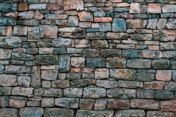 Background in the form of a granite stone wall with a fallen solution and different sizes of stones. The old colored bricks are faded and gray with age.