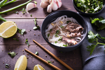 Asian cuisine, Vietnamese pho bo soup in a black plate on a wooden background