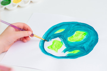 Child draws planet for earth day. Protection of environment. Earth Day celebration. Save world and unity concept.