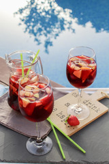 Spanish red wine (Sangria) with fruit. Strawberry, orange, Apple and banana slices. On a tray next to the pool