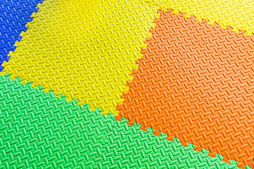 Colorful jigsaw tiles, foam floor tiles or mats in yellow, blue, green, and orange. Use for kids or kindergarten for anti-slip surfaces and backgrounds.