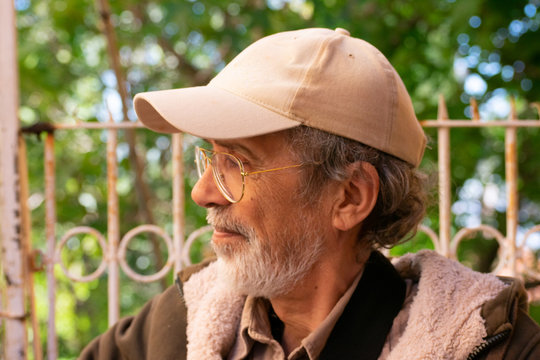 Old middle Eastern man wearing baseball cap and eyeglasses in profile
