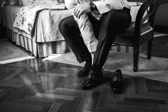 businessman ties shoelaces on shoes close-up. men's hands and a pair of leather shoes. business men's morning. black and white photo
