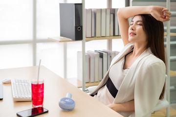 Asian woman suffers from heat while working in the office with cold water