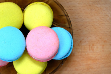 Colorful french Sweet Pastries Macaroons on glass plate on a wooden tray isolated on white background.