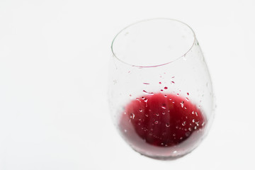 glass of red wine with drops on a white background, copyspace