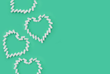 Mock up dessert composition with marsmallow hearts on mint background. Minimal greeting concept for Christmas, Valentines day, Mothers day, birthday or wedding. Flatlay with copyspace.