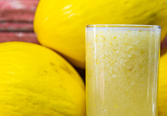 Spanish melon juice (Cucumis mello) and fruits on aged red wooden background