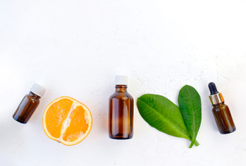 Mock up  aromatherapy flatlay with orange essential oil bottles, citrus and leaves on white background. Spa, natural cosmetic and healthcare concept. Detox, anti-cellulite effect. Top view. Copyspace.